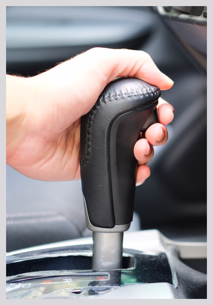 Hand gripping an automatic gear shift inside a car