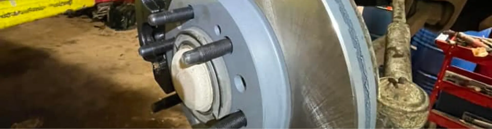A close-up shows a gray brake rotor with wheel studs, likely during a brake repair in Canadian Lakes, MI at 2nd Mile Repair.