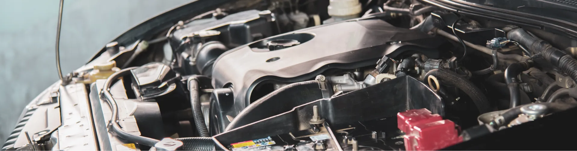 A detailed view of a car engine bay, showing various mechanical components, wiring, and hoses.