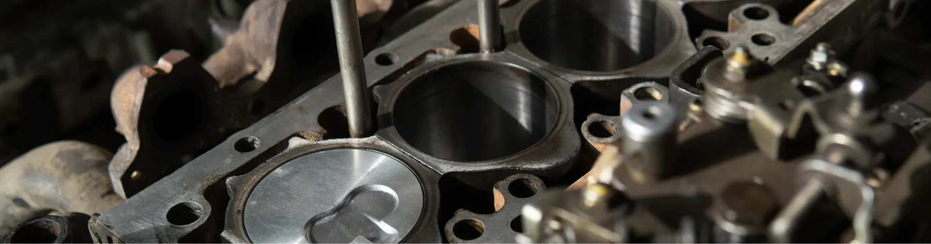 A close-up of an engine block with visible cylinders and pistons, suggesting an engine overhaul or repair.