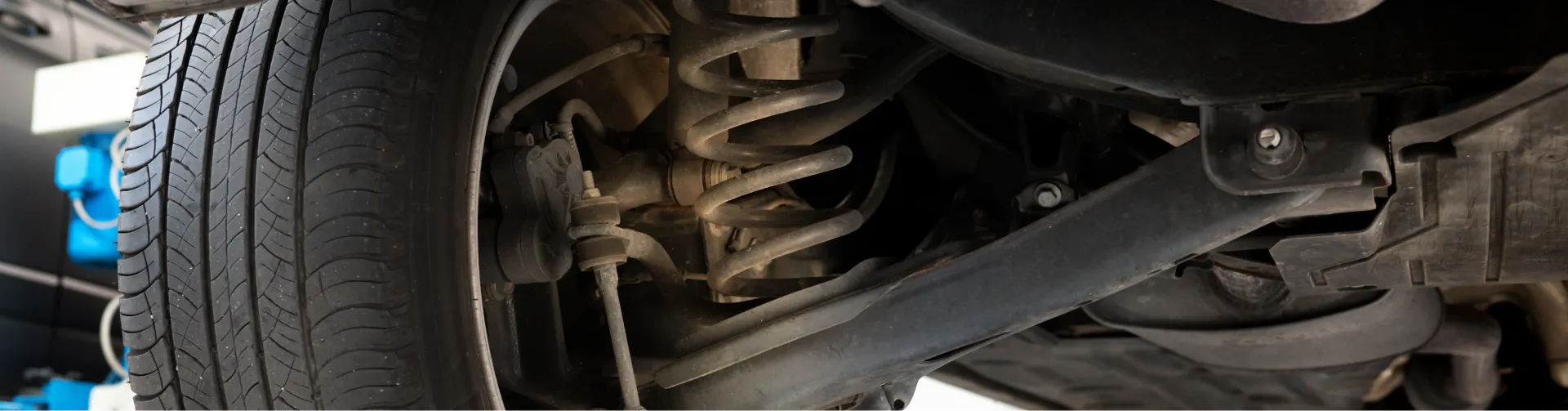 A view underneath a vehicle, showing the tire, suspension coil spring, and other undercarriage components.